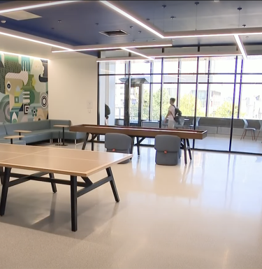 A bright room with windows and ping pong tables.