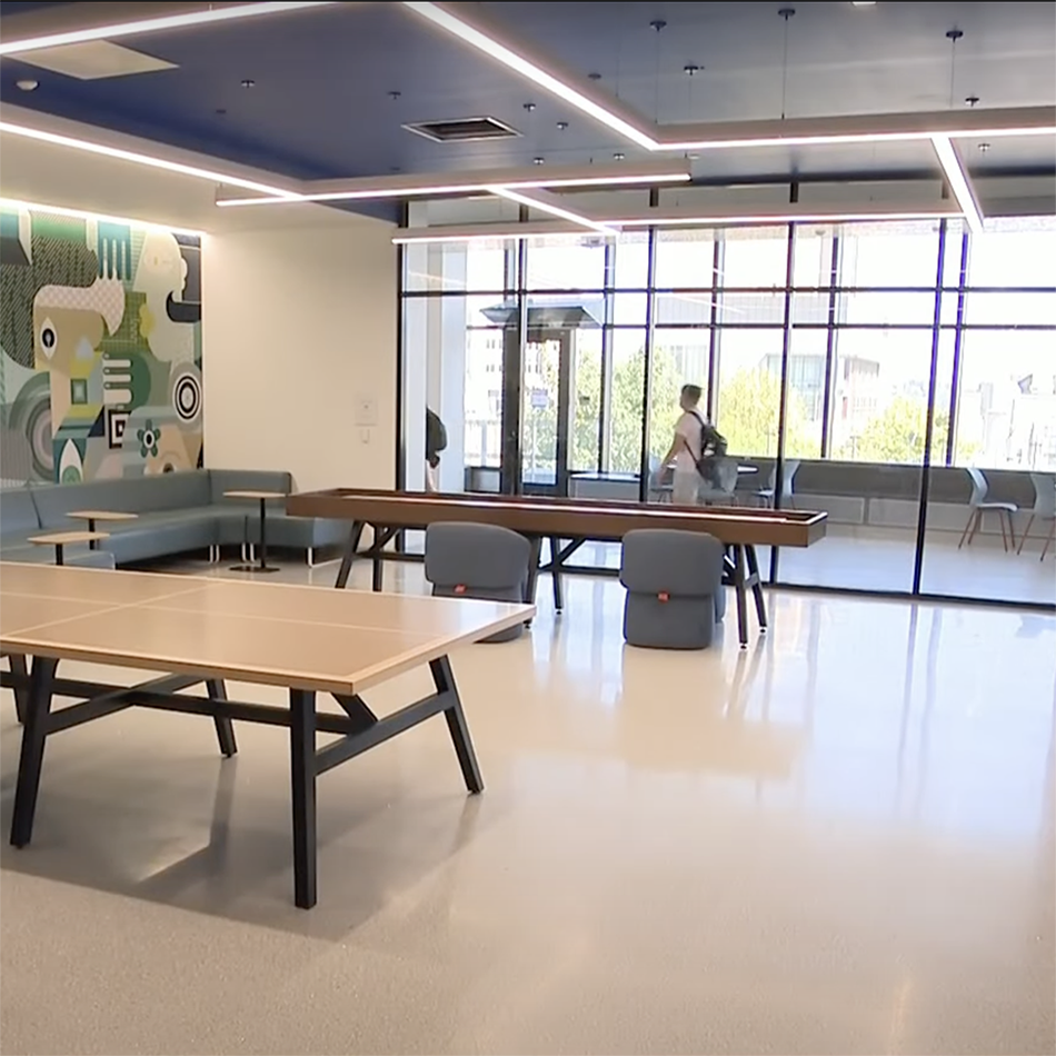 A bright room with windows and ping pong tables.